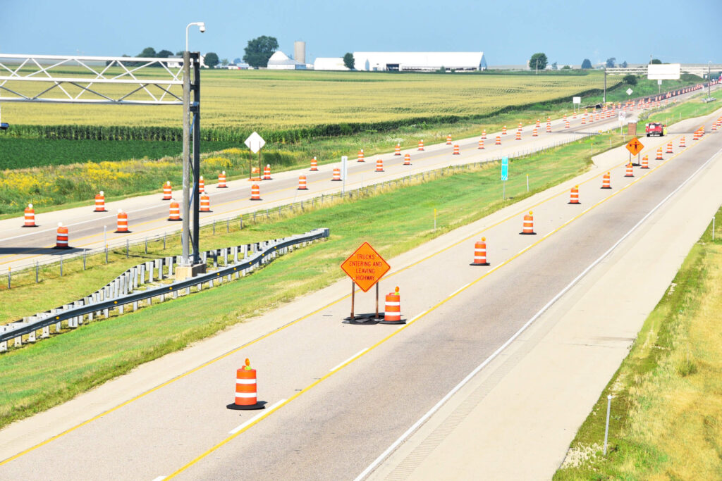 A large stretch of highway with many safety barrels