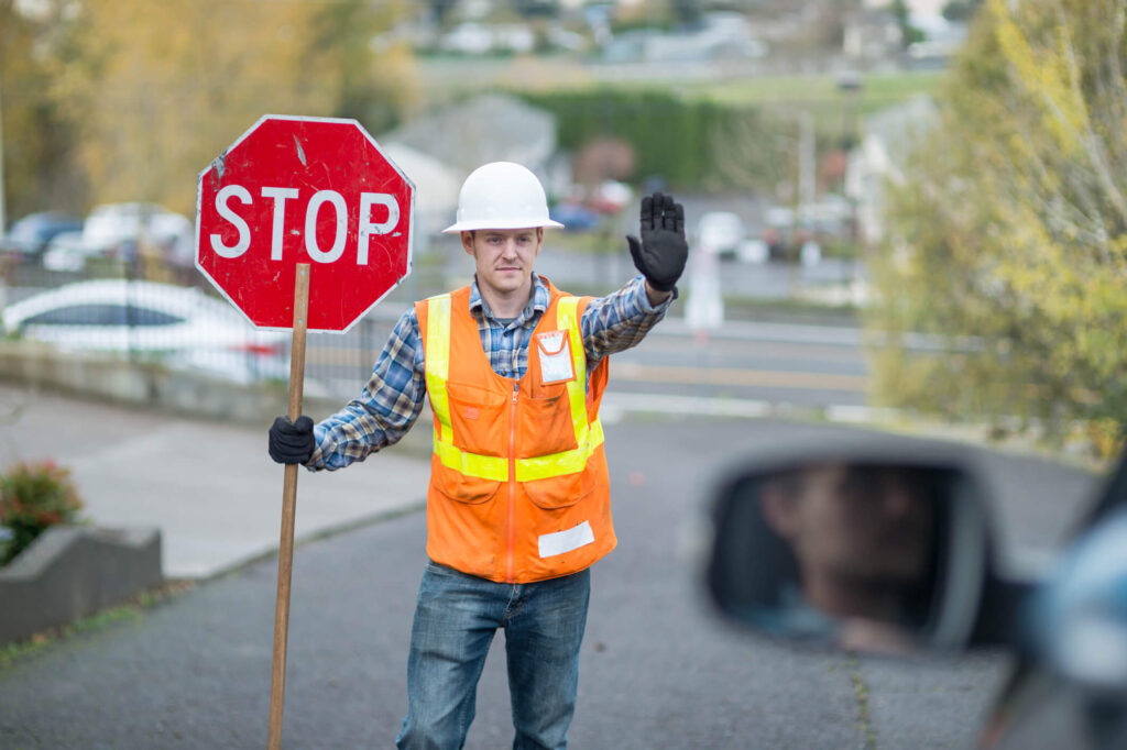 Man holding stop sign with hand out in halt motion