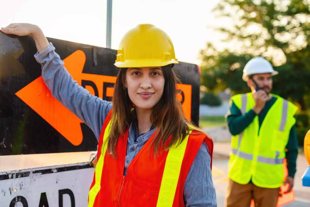 Woman wearing safety hat and vest looking at camera